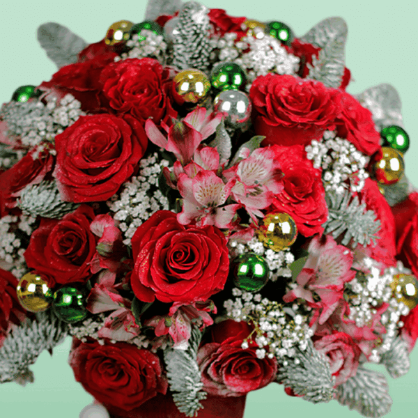 Christmas floral arrangement with festive red blooms, seasonal greenery, ornaments, and a wrapped Christmas present, beautifully designed for holiday celebrations and gifting.