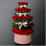 Stunning rose layer arrangement featuring passionate long-stem red roses arranged in tower shape in a pink box.