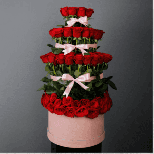 Stunning rose layer arrangement featuring passionate long-stem red roses arranged in tower shape in a pink box.