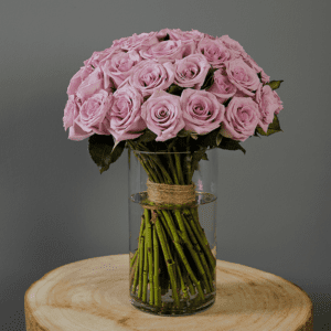 Hand-tied, bunch of purple roses in a glass cylinder vase