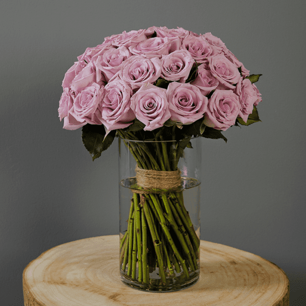 Hand-tied, bunch of purple roses in a glass cylinder vase