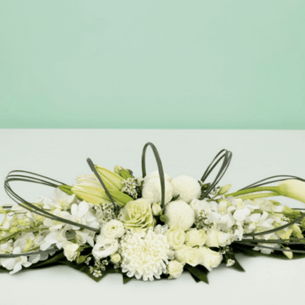 White long and low floral arrangement featuring elegant white roses, orchids, hydrangeas, and seasonal blooms in a modern centerpiece design for weddings, events, and luxury table décor.