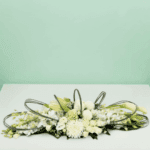 White long and low floral arrangement featuring elegant white roses, orchids, hydrangeas, and seasonal blooms in a modern centerpiece design for weddings, events, and luxury table décor.