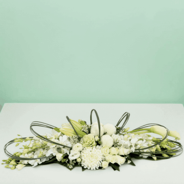 White long and low floral arrangement featuring elegant white roses, orchids, hydrangeas, and seasonal blooms in a modern centerpiece design for weddings, events, and luxury table décor.