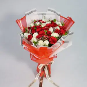 A breathtaking red and white roses bouquet, elegantly wrapped in matching red and white paper, accented with lush greenery for a touch of freshness.