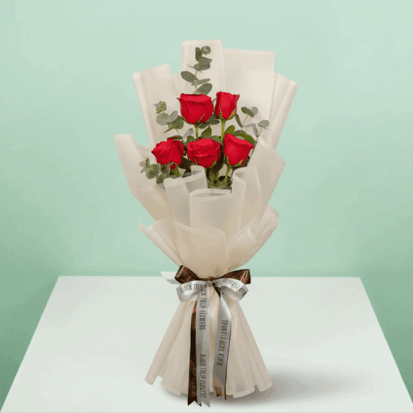 A bouquet of 5-stem red rose bouquet with soft greens wrapped in a White sheet