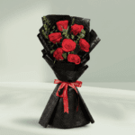 A hand bouquet of 7 red roses, all tied together in a Black non woven paper with a red ribbon.