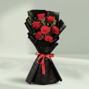 A hand bouquet of 7 red roses, all tied together in a Black non woven paper with a red ribbon.