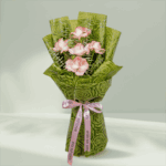 A Bouquet of 5 pink roses with eucalyptus leaves in green wrap tied up in a pink ribbon