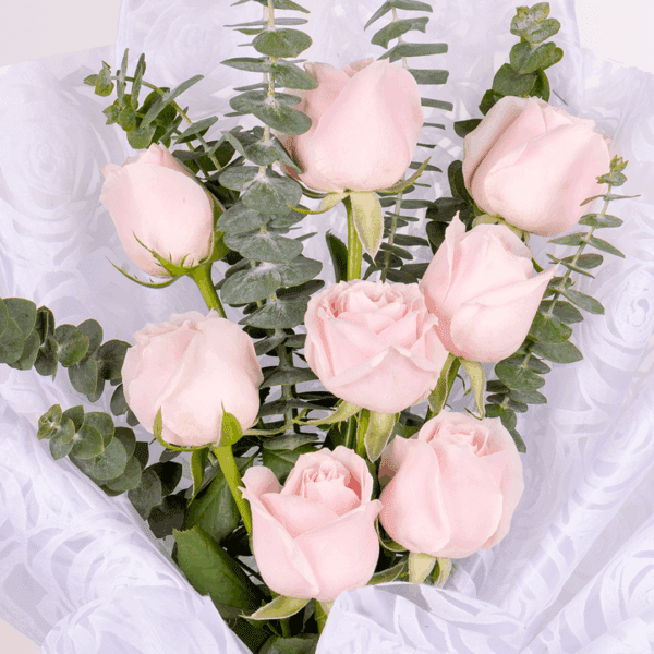 Pink rose and eucalyptus bouquet wrapped in soft floral non-woven paper
