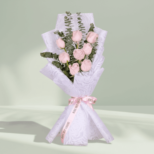 Pink rose and eucalyptus bouquet wrapped in soft floral non-woven paper