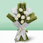 A Bouquet of 7 white roses wrapped in green and white paper.
