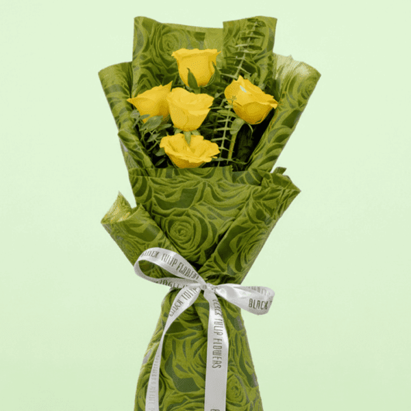 A Bouquet of 5 yellow roses bouquet with green wrap tied up in a pink ribbon
