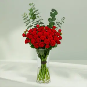 A bunch of Fresh red roses and eucalyptus arranged in a cute glass vase