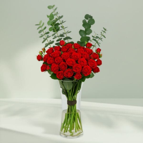 A bunch of Fresh red roses and eucalyptus arranged in a cute glass vase