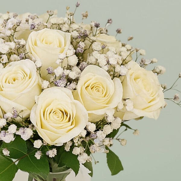 Glass transparent vase with white roses and baby’s breath
