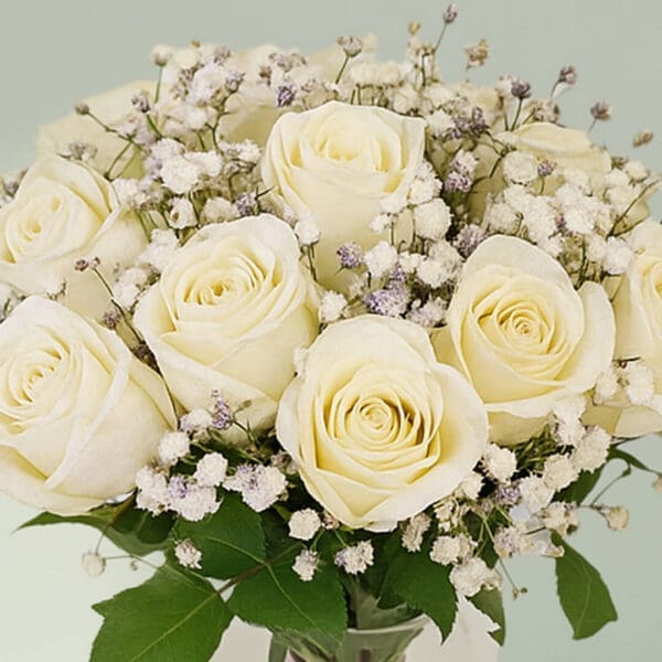 Glass transparent vase with white roses and baby’s breath