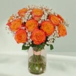 A bunch of orange roses with gypso in a transparent glass