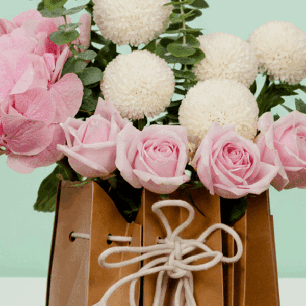 A soft-toned hydrangeas, ping pong blooms, and roses, gently arranged with eucalyptus leaves—all nestled in a chic, eco-friendly paper bag.