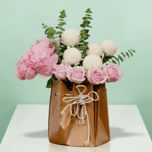 A soft-toned hydrangeas, ping pong blooms, and roses, gently arranged with eucalyptus leaves—all nestled in a chic, eco-friendly paper bag.