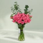 A bunch of Pink roses and eucalyptus in glass vase
