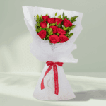 Vibrant red roses with fresh green leaves, elegantly wrapped in white non-woven paper and tied with a bright red satin ribbon.