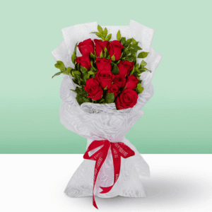 12 rich red roses with green leaves, wrapped in a white, textured non-woven paper and tied with a bright red ribbon.