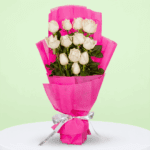 Bouquet of 12 white roses with green leaves, wrapped in bright fuchsia pink non-woven paper and tied with a white and black ribbon.
