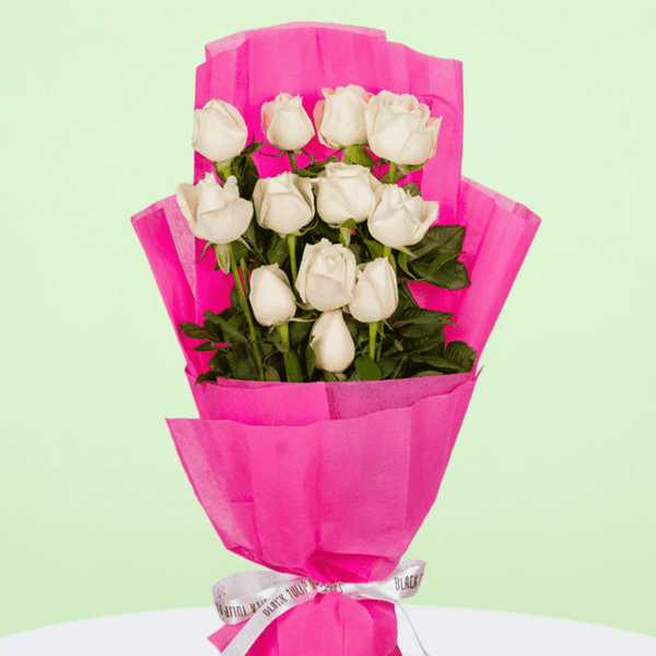 Bouquet of 12 white roses with green leaves, wrapped in bright fuchsia pink non-woven paper and tied with a white and black ribbon.