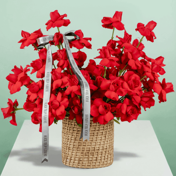 Round basket of 50 red roses arranged neatly with a white ribbon