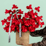 Round basket of 50 red roses arranged neatly with a white ribbon