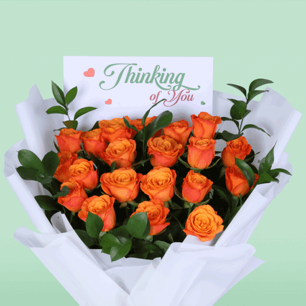 Hand-tied orange rose flower bouquet styled with white wrapping and printed message card saying 'thinking of you'