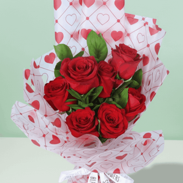 Romantic red rose bouquet with fresh green leaves, wrapped in elegant Korean-style flower sheets