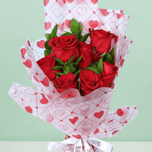 Romantic red rose bouquet with fresh green leaves, wrapped in elegant Korean-style flower sheets