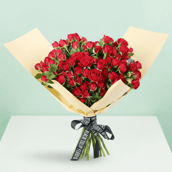 A luxurious arrangement of vibrant red roses, beautifully gathered and wrapped in non-woven paper.