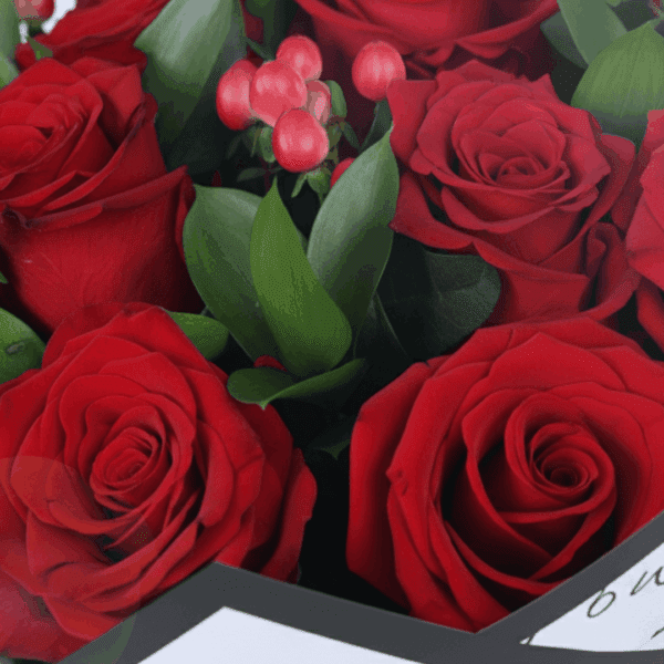Mixed red floral bouquet with roses, hypericum, and green leaves, styled in trendy Korean wrapping.