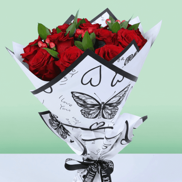 Mixed red floral bouquet with roses, hypericum, and green leaves, styled in trendy Korean wrapping.