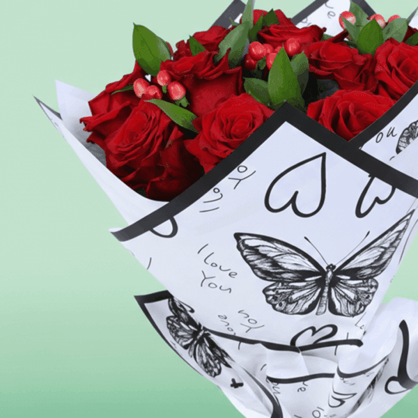 Mixed red floral bouquet with roses, hypericum, and green leaves, styled in trendy Korean wrapping.