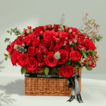 Rectangle basket arrangement of red roses, spray roses, hypericum, and eucalyptus with a Valentine’s topper