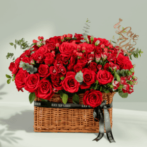 Rectangle basket arrangement of red roses, spray roses, hypericum, and eucalyptus with a Valentine’s topper