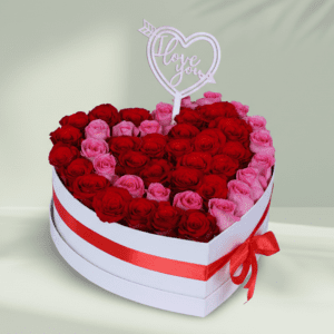 Heart-shaped white box filled with red and pink roses tied with a ribbon