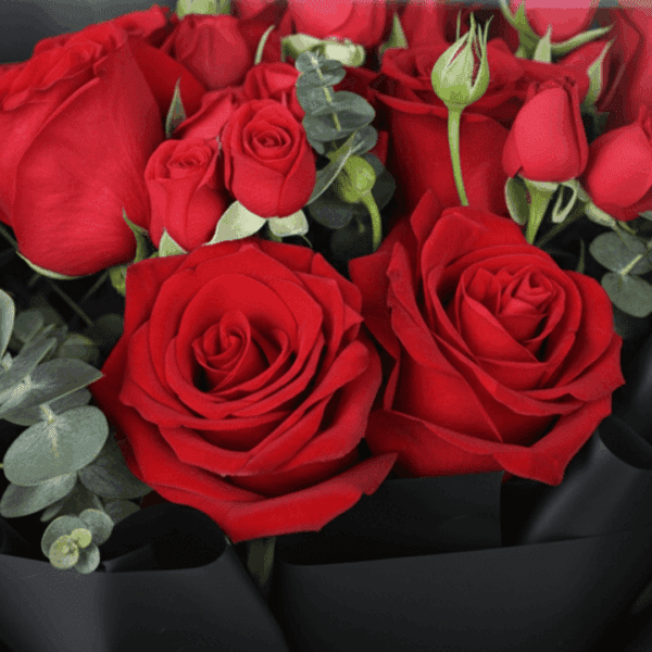 "Red roses with delicate spray roses and eucalyptus, wrapped in elegant black Korean-style flower sheets"