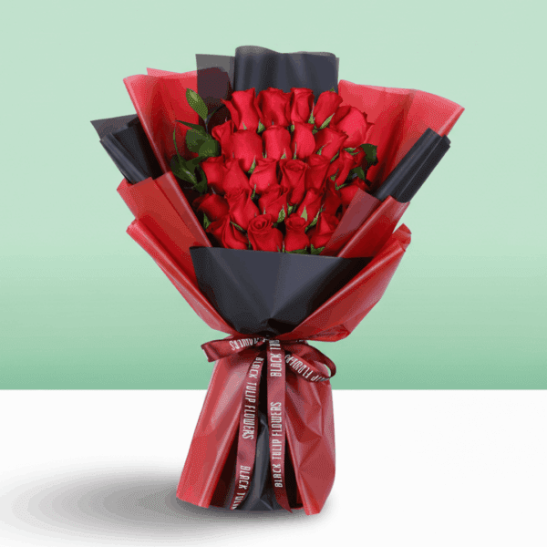 Fresh red roses arranged in a compact bouquet, wrapped in a black and red sheet and tied with a red ribbon