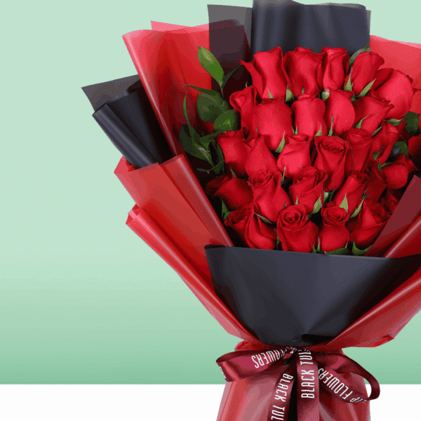 Fresh red roses arranged in a compact bouquet, wrapped in a black and red sheet and tied with a red ribbon