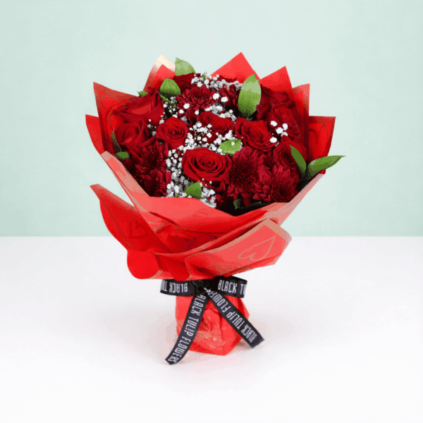 "Romantic red floral arrangement with roses, chrysanthemums, green leaves, and a golden “Love You” topper in Korean wrapping. "