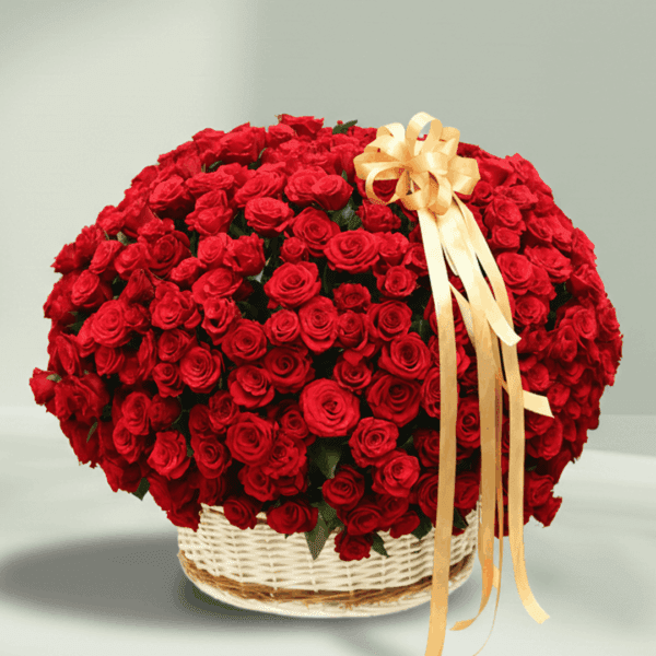 An overflowing arrangement of red roses in a white wicker basket, finished with a gold ribbon.
