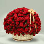 An overflowing arrangement of red roses in a white wicker basket, finished with a gold ribbon.