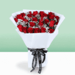 Red roses bouquet with baby’s breath wrapped in white and tied with a black ribbon.