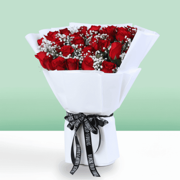 Red roses bouquet with baby’s breath wrapped in white and tied with a black ribbon.