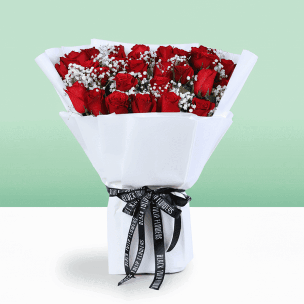 Red roses bouquet with baby’s breath wrapped in white and tied with a black ribbon.